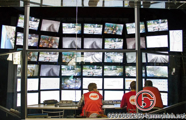 Ba người kỹ sư tại trung tâm của phòng điều khiển có 40 máy tính và 6 hàng màn hình Ba người kỹ sư tại trung tâm của phòng điều khiển có 40 máy tính và 6 hàng màn hình