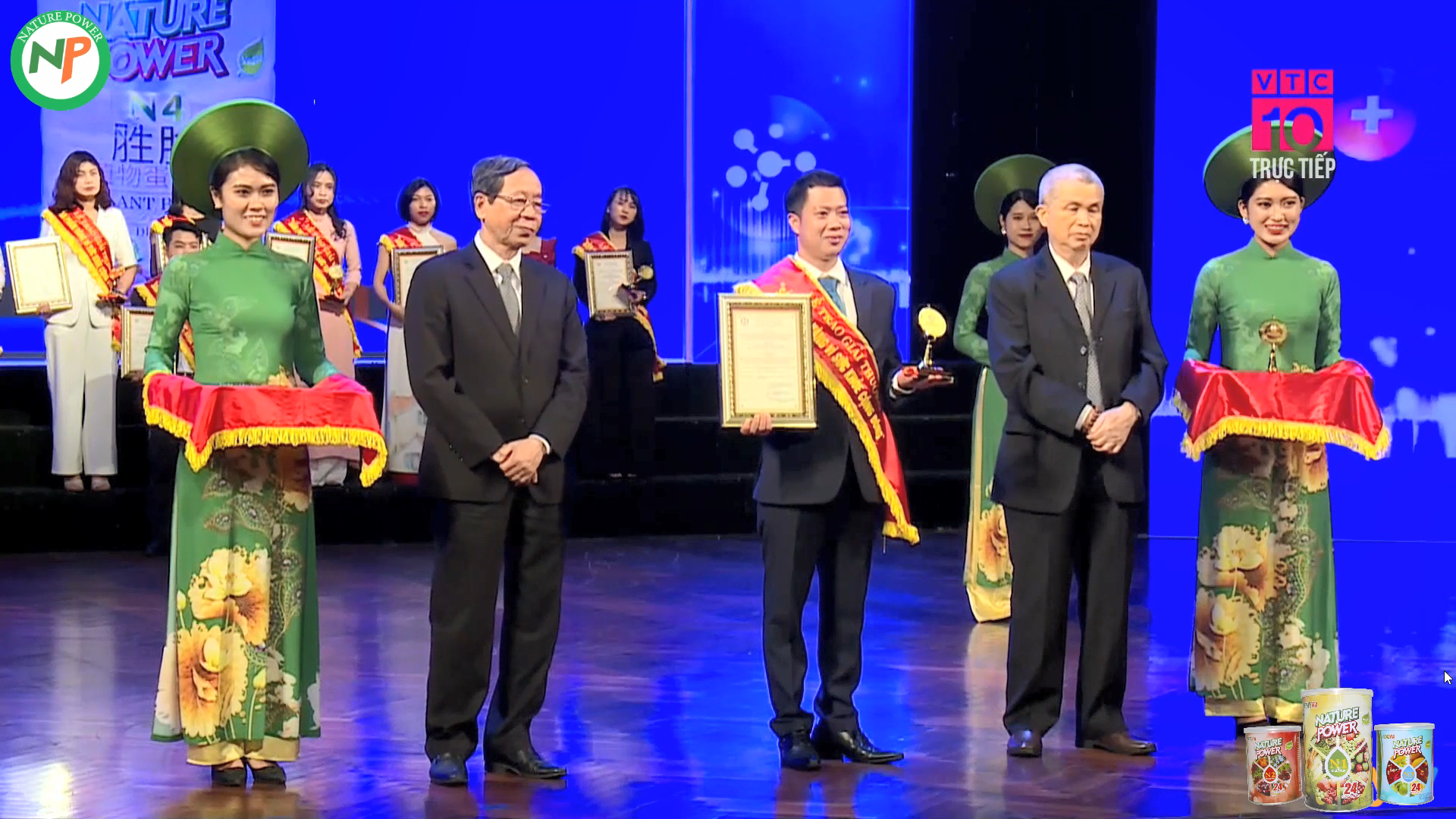 Ông Hoàng Văn Tuấn - Đại Diện Văn Phòng Dinh Dưỡng NP Miền Bắc nhận giải thưởng "Sản phẩm vàng vì sức khỏe cộng đồng 2024" (ở giữa). PGS.TS Trần Đáng - chủ tịch Hiệp Hội TPCN Việt Nam, Nguyên Cục Trưởng Cục An Toàn Thực Phẩm (áo vest bên phải). TS.Nguyễn Bá Thủy - Nguyên Thứ Trưởng Bộ Y Tế (áo vest bên trái)