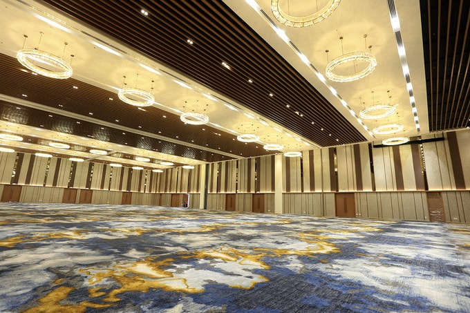 ben-trong-hoi-nghi-duoc-thiet-ke-voi-phong-cach-nghe-thuat-duong-dai Bên trong hội nghị được thiết kế với phong cách nghệ thuật đương đại. Sảnh trải những tấm thảm dệt hoa văn chìm gắn với hội hoạ Gothic, trang trí những tấm phù điêu lớn bằng gỗ do các nhà thiết kế Italy chế tác riêng, tường kết hợp hài hòa giữa gỗ, vải và gương kính