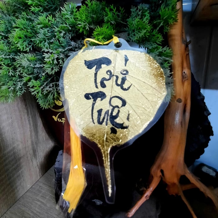 Lá bồ đề dát vàng viết tay chữ thư pháp chữ TRÍ TUỆ có ép plastic  