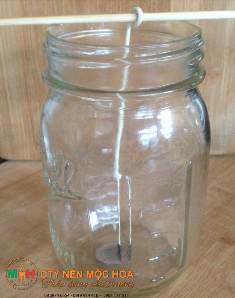 Quấn một đầu sợi bấc lên một xiên gỗ hoặc bút chì và đặt ngang chiếc xiên gỗ này lên miệng lọ thủy tinh Quấn một đầu sợi bấc lên một xiên gỗ hoặc bút chì và đặt ngang chiếc xiên gỗ này lên miệng lọ thủy tinh