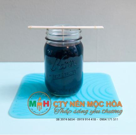 Cẩn thận đổ sáp nóng chảy vào lọ thủy tinh Cẩn thận đổ sáp nóng chảy vào lọ thủy tinh