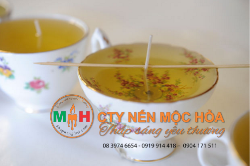 Dùng một chiếc que gỗ đặt trên miệng tách để giúp sợi bấc đứng thẳng. Dùng một chiếc que gỗ đặt trên miệng tách để giúp sợi bấc đứng thẳng.
