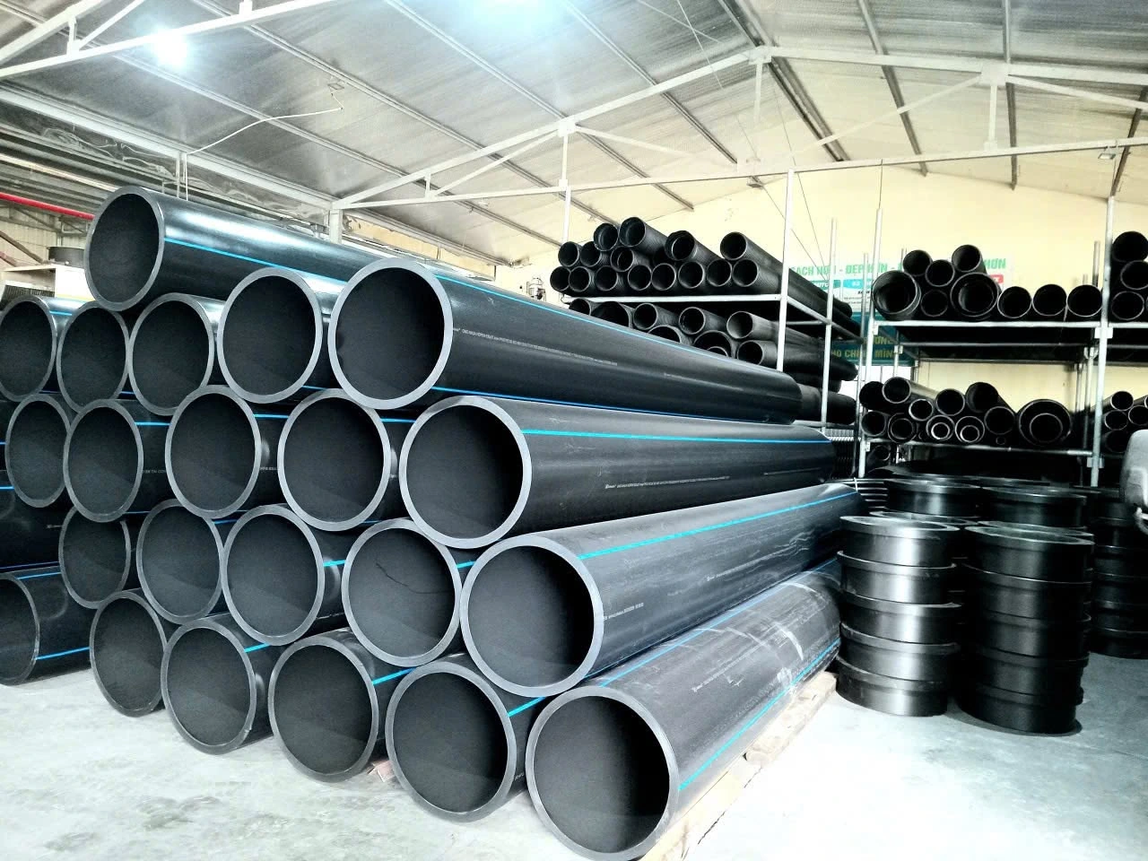 Ống HDPE màu đen sọc xanh dạng cây thẳng xếp trong kho, nhìn rõ mặt cắt đầu ống