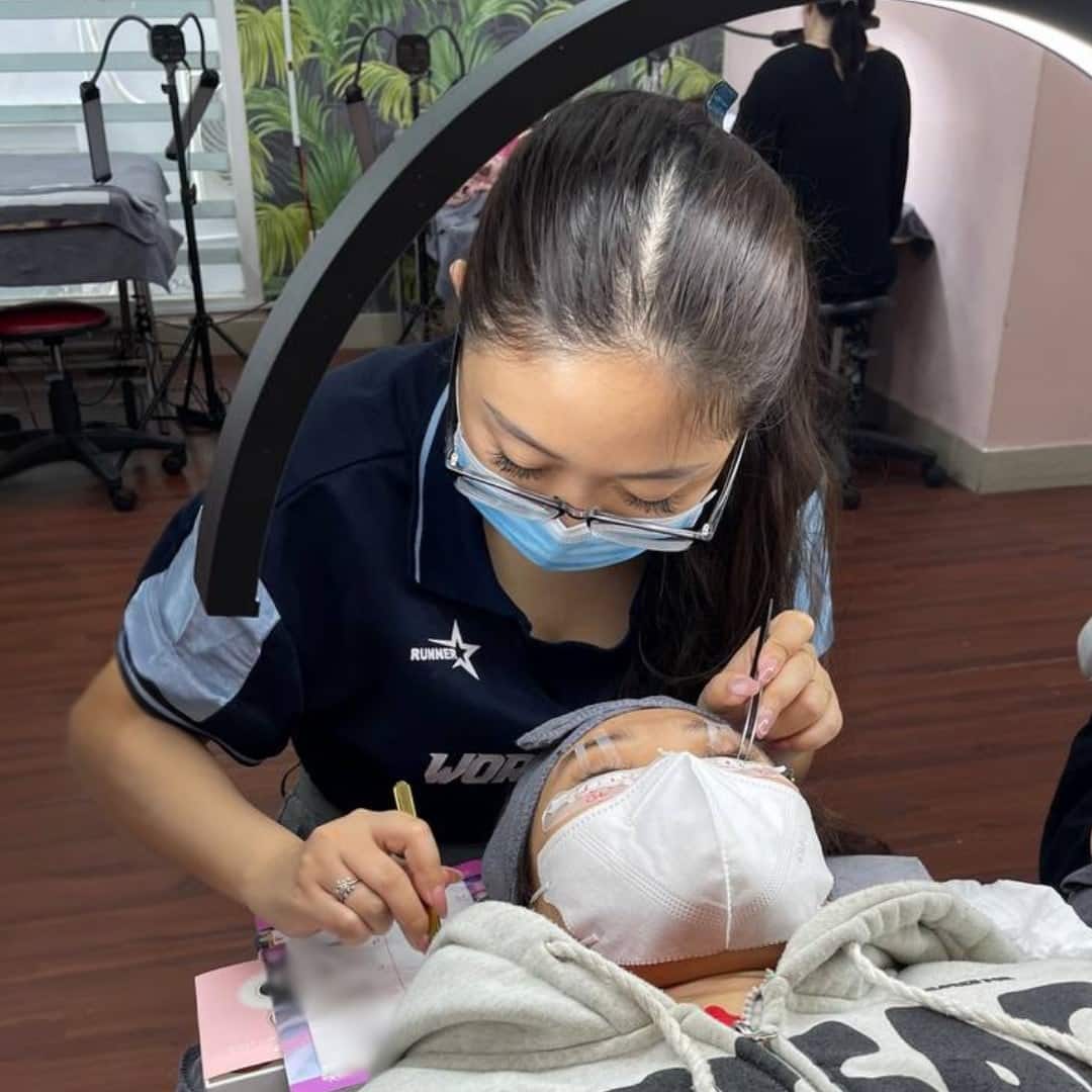 Khách hàng được tư vấn loại keo nối mi phù hợp trong salon.