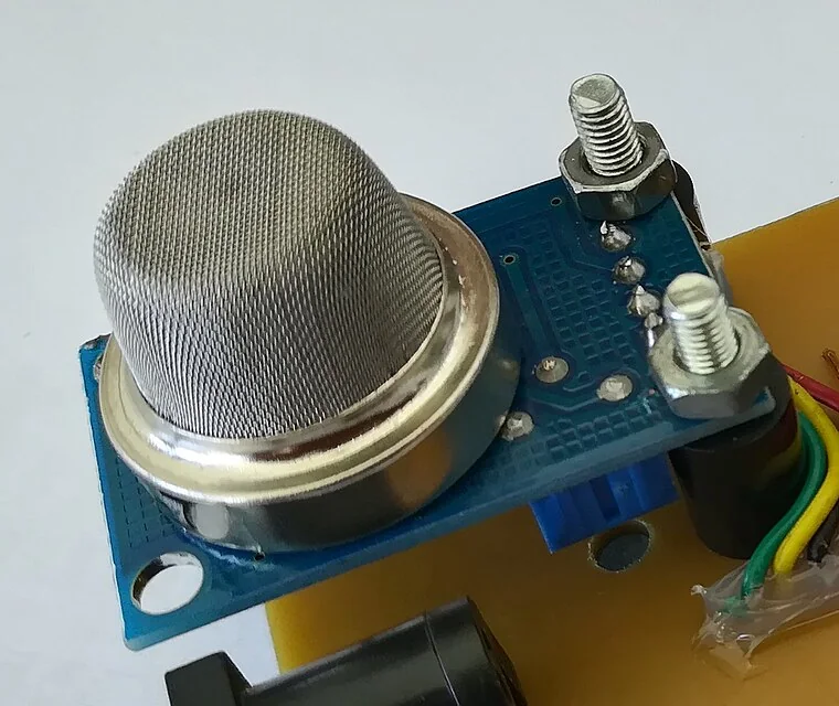 Cảm biến khí bán dẫn nắp lưới thép không gỉ hình trụ gắn trên module mạch in màu xanh, bắt vít lên một tấm mạch tự làm, có dây nối ra