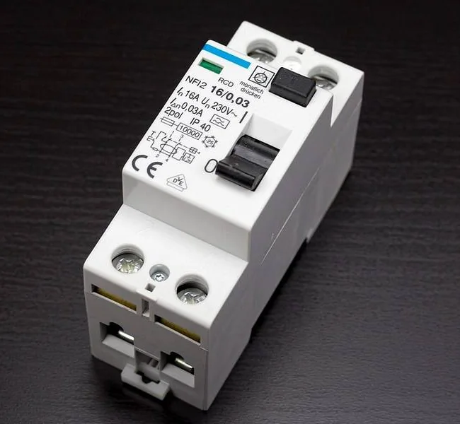 Ảnh chụp một thiết bị chống giật hai cực gắn thanh ray màu trắng, nhãn ghi dòng định mức 16 A, dòng rò tác động 0,03 A, điện áp 230 V, có cần gạt bật tắt và nút thử