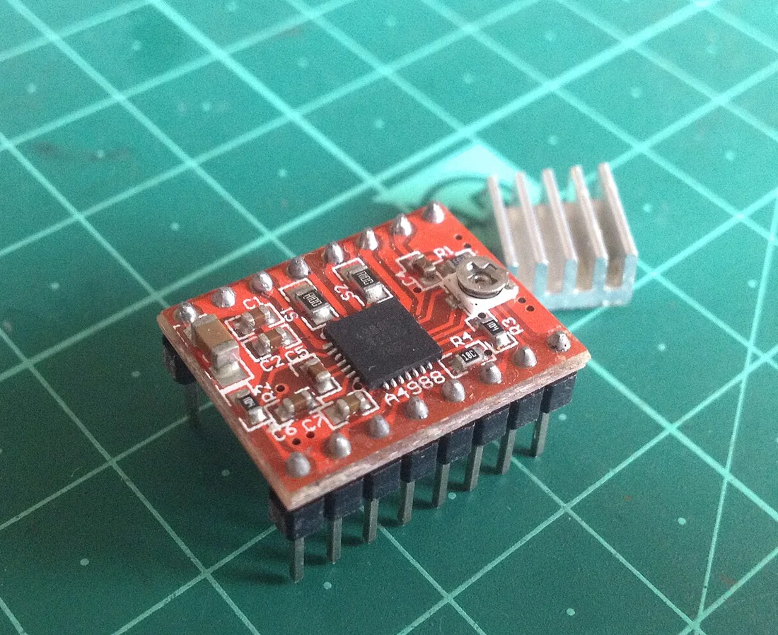 Module driver động cơ bước A4988 màu đỏ với hai hàng chân cắm, biến trở chỉnh dòng nhỏ và miếng tản nhiệt nhôm đặt bên cạnh