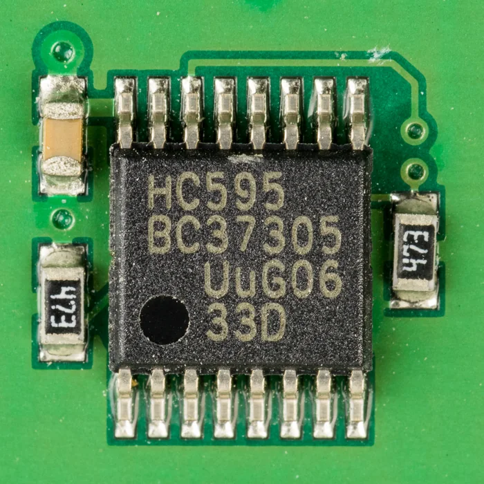 Ảnh chụp cận cảnh IC thanh ghi dịch HC595 vỏ TSSOP 16 chân màu đen hàn trên mạch in xanh lá, trên thân in chữ HC595 và các dòng mã, chấm tròn đánh dấu chân 1, hai bên là tụ và điện trở dán ghi 473
