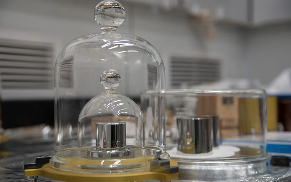 Các quả cân kilogam mẫu bằng hợp kim platin iridi đặt dưới hai lớp chuông thủy tinh trong phòng thí nghiệm