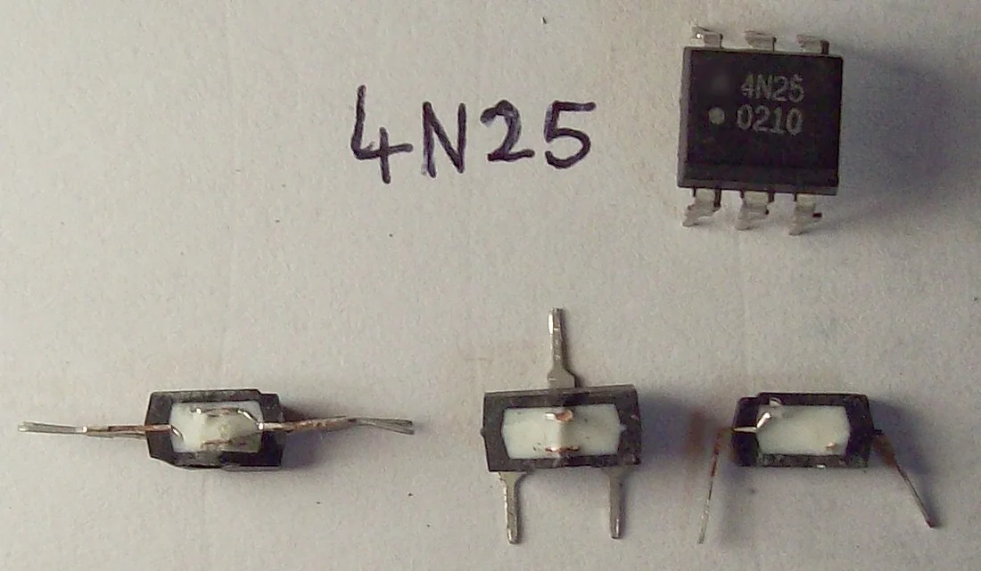 Ảnh chụp một optocoupler 4N25 vỏ DIP 6 chân màu đen ở góc trên, chữ 4N25 viết tay bên cạnh, phía dưới là ba chiếc optocoupler đã cắt bỏ vỏ đen để lộ khối nhựa trắng bên trong và các chân kim loại