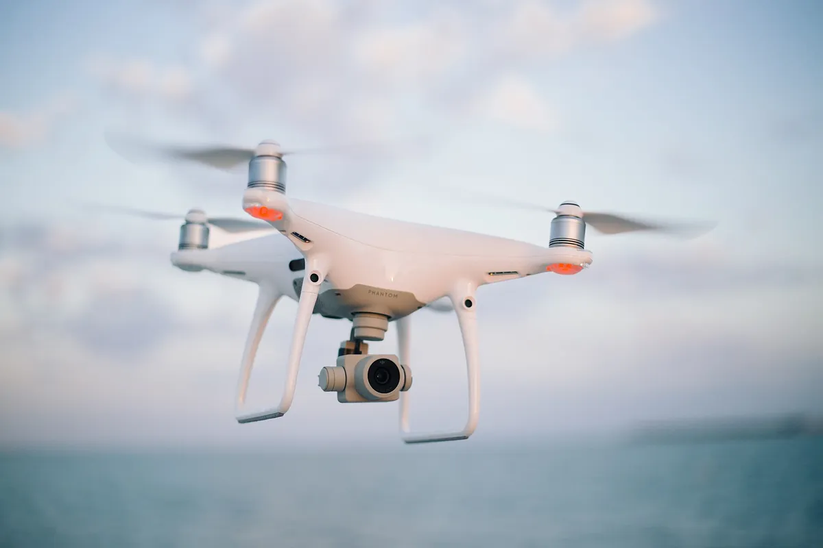 Flycam bốn cánh đang bay trên mặt biển, camera treo trên gimbal phía dưới thân máy