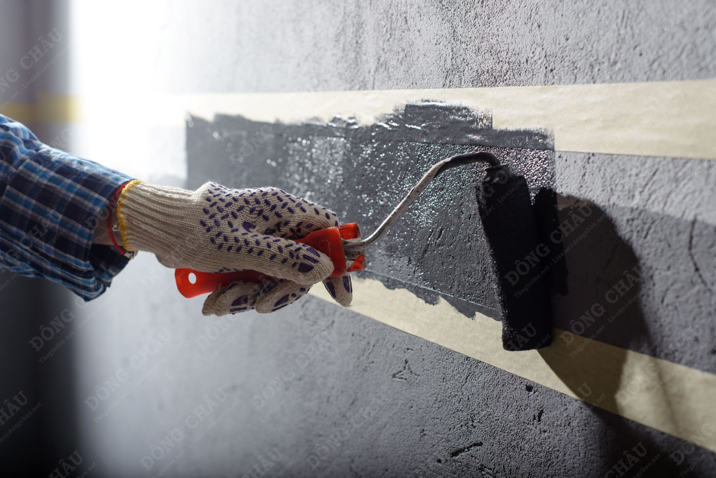 một người phụ nữ dùng băng keo giấy để vẽ lên tường