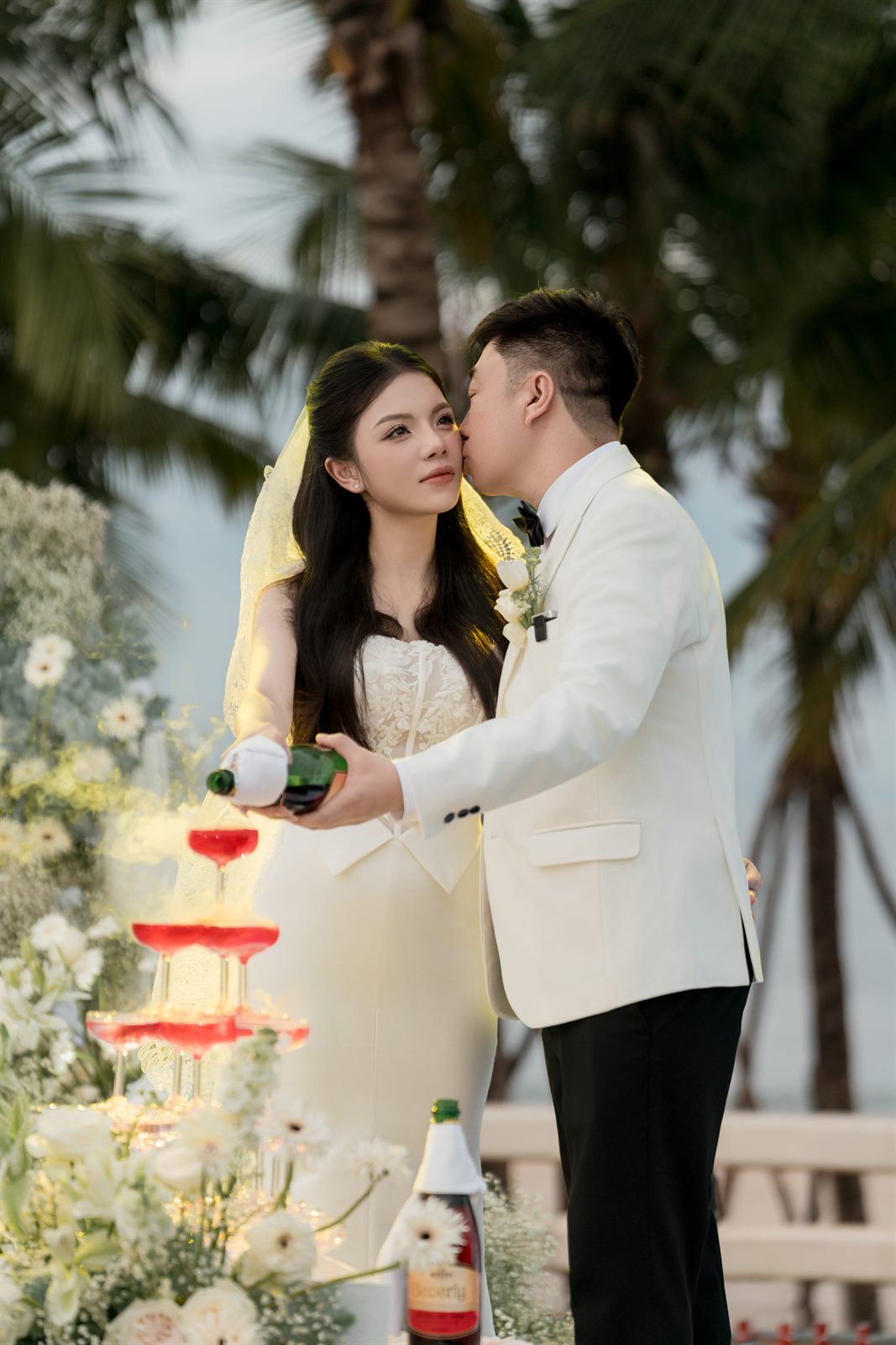 Chú rể hôn má cô dâu bên tháp ly
