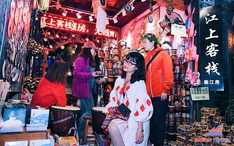 Khách du lịch có thể tạo dáng trước cửa hàng lưu niêm đầy màu sắc trên các con phố Phượng Hoàng cổ trấn Khách du lịch có thể tạo dáng trước cửa hàng lưu niêm đầy màu sắc trên các con phố Phượng Hoàng cổ trấn